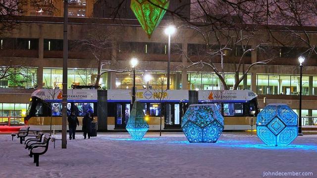 The Hop streetcar stopping at Cathedral Square where the Lightfield sculptures are on display in the snow night.