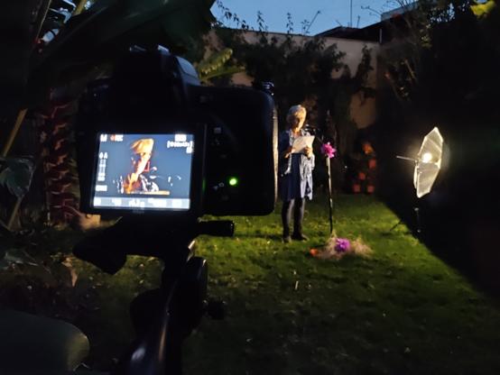 En un jardín de Tepoztlán, una participante del programa Under The Volcano lee en evento de micrófono abierto, ante una cámara de video