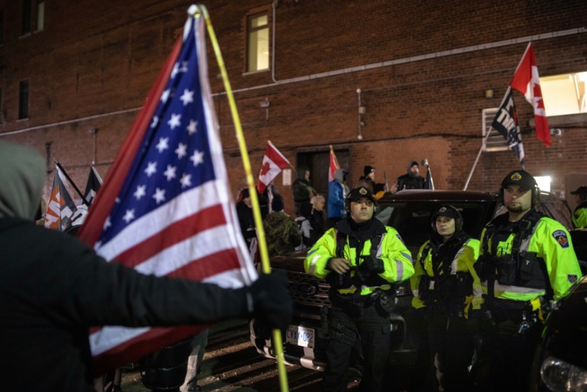 Freedumb Convoy idiots in Hamilton, Ontario, in January 2023, outside of the Sheraton Hotel where the Liberal cabinet retreat was taking place. They have a US flag as well as F*** Trudeau and other flags, and are facing off with police.