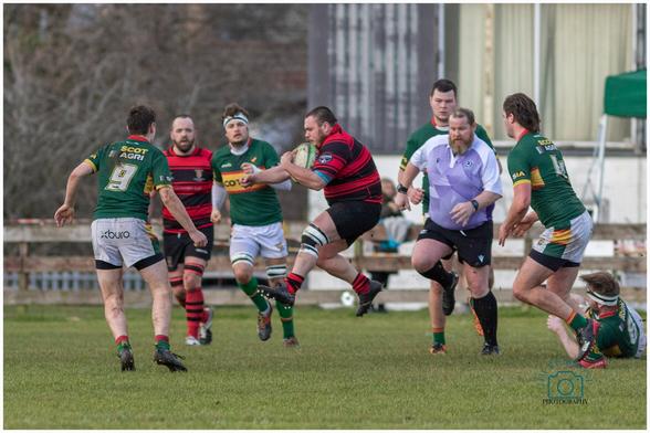 A game of rugby. Cambuslang players in green, gold and white, Cumnock players in red and black.