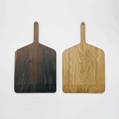 Two pizza paddles side by side. The left is made with walnut and the right is oak.
