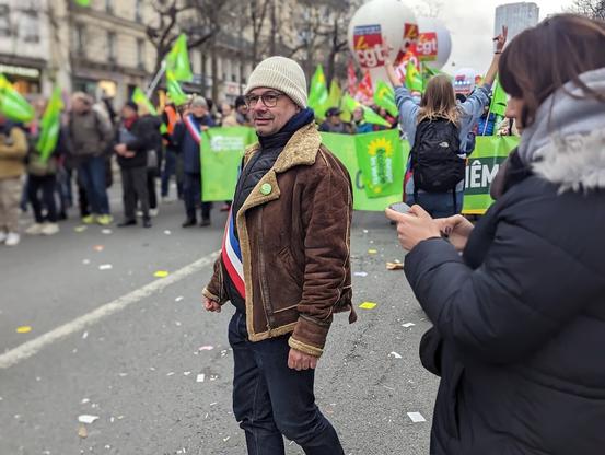 Rodéric Aarsse, bonnet blanc et veste en cuir molletonée, avec son écharpe d'adjoint municipal, en tête du cortège EELV, lors de la manifestation parisienne du mardi 31 janvier 2023.