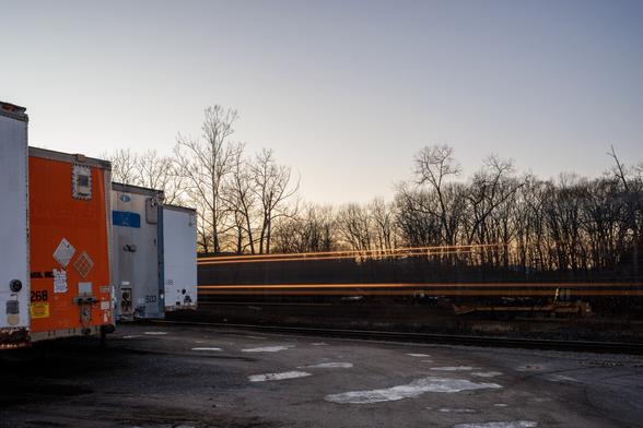 long exposure of a train passing some parked trucks