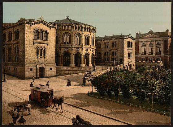 Historical Library of Congress photo of a horse-drawn trolley running on tracks in front of  Norwegian parliament buildings