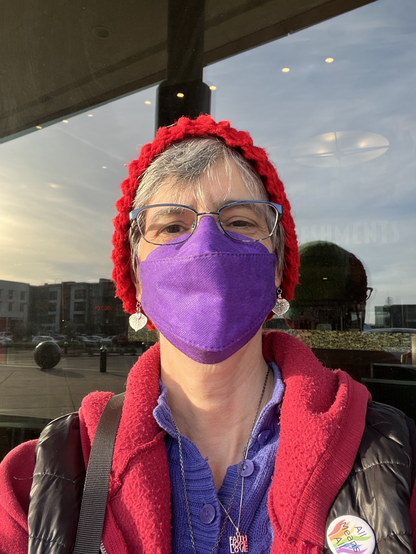 Happy woman in purple sweater, red hat and purple mask
