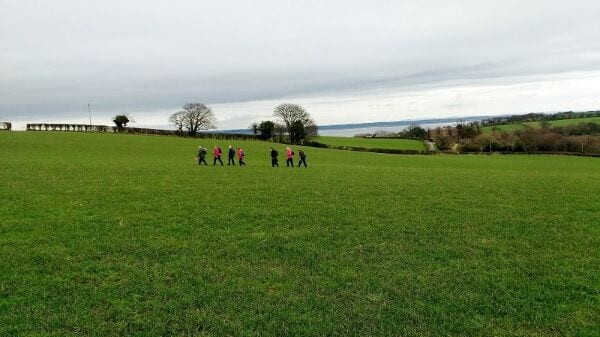View of walkers crossing a field on an overcast day
