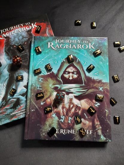 Zwei Bücher zu Journey to Ragnarok - Welt und Abenteuer und The Rune Thief, umgeben von Runensteinen und mit zwei Runenwürfeln.