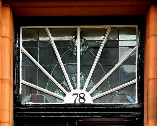 A small rectangular window over a front door has been divided into wedges to create a sunburst effect.