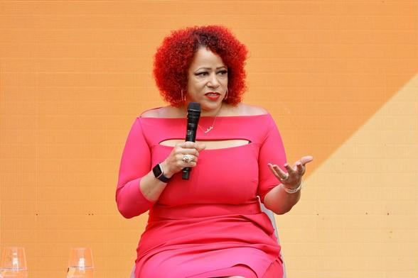 Black woman Nikole Hannah-Jones holding a microphone during a speech on stage