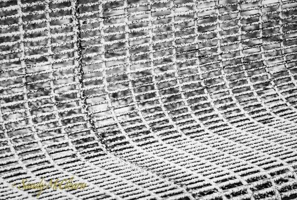 Ice crystals on a metal wire frame park bench.