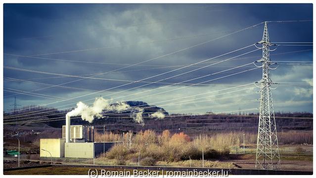A powerststion and an electrical network in front of a dark sky.