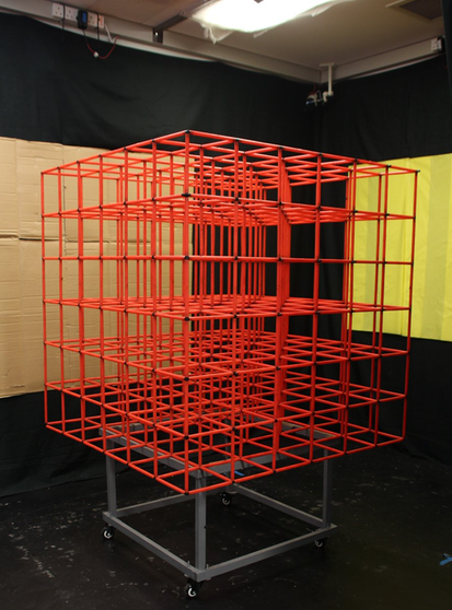 Photo of the 3d lattice maze used in the experiment, elevated, made of red plastic bars. Note the multiple tracking cameras on the ceiling. Photo by Roddy Grieves.