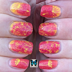 A pic of nails showing a thermal polish in its cold state of a sunset red, with dandelion flowers stamped in pink and yellow.