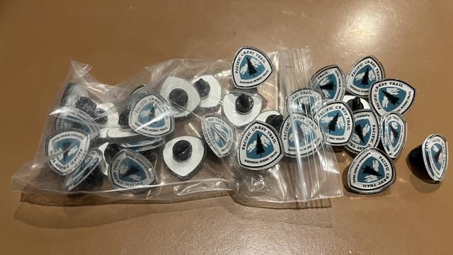 A bag of pins with the pacific crest trail emblem