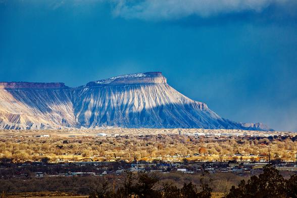 Desert mountain with a little snow on top with a small city in the foreground.