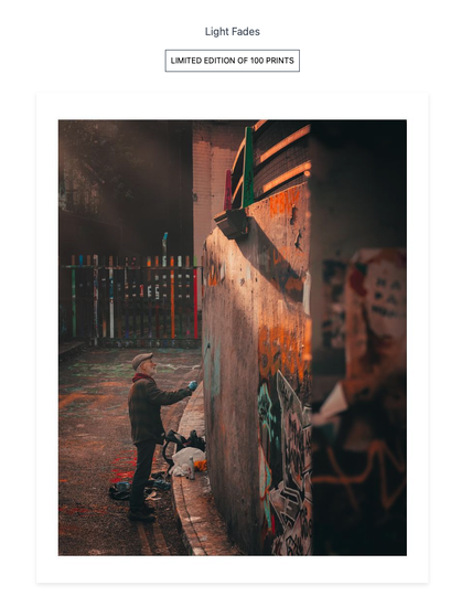 A shot of a fine art print showing an older man paint graffiti bathed in sunlight