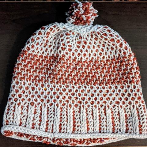 The same hat but first effort so less pretty. This has grey as the dominant color and red as secondary. Instead of a ponytail, it ends with a Pom Pom so it makes a slouchy beanie. The lattice is more rounded than diamond on this version.