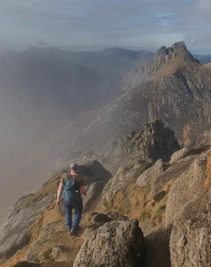 Man walking in rocky mountains with low cloud