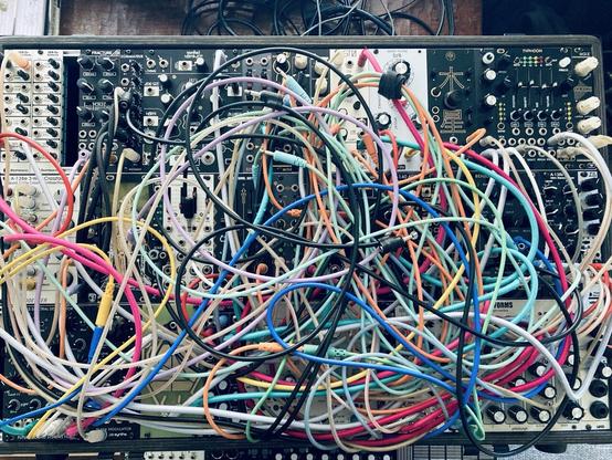 A modular synth covered in a mass of multicolored cables