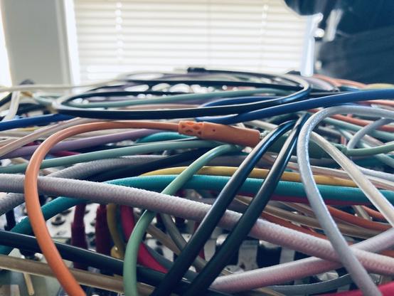 A modular synth covered in a mass of multi-colored cables