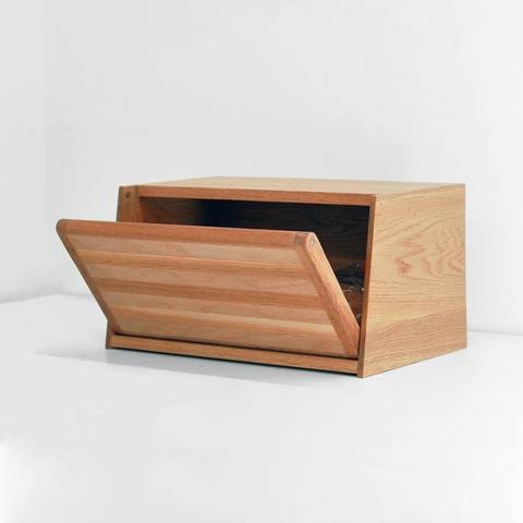 An oak bread box with the door slightly ajar.