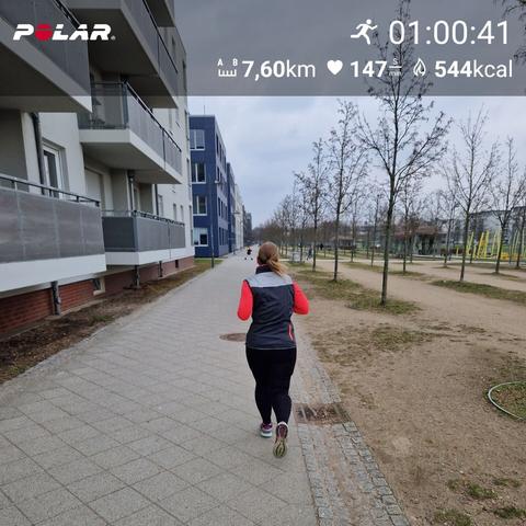 Ich beim Lauftraining, Läuferin von hinten fotografiert auf einem gepflasterten Weg, links Häuser, rechts Park. Oben Specs des Laufs: 1 Stunde, 7,6 km, 147 HF im Schnitt und 544 kcal verbrannt.
