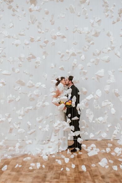 Bride and groom posing behind an art installation of floating white rocks at the Milwaukee Art Museum