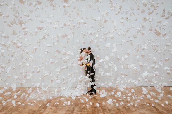 Bride and groom posing behind an art installation of floating white rocks at the Milwaukee Art Museum