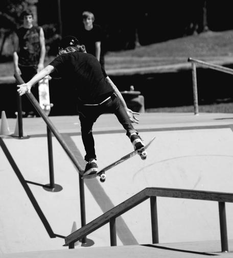Skateboarder flies off steel rail; aerial action shot.