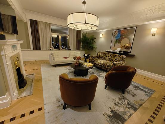Large and bright living room described as "modern with an art nouveau twist" including a fireplace and some art pieces.