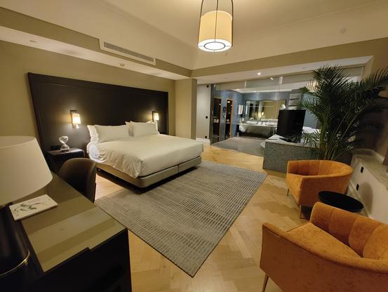 Spacious bedroom with a king bed, work desk, smart TV, and additional seating.
