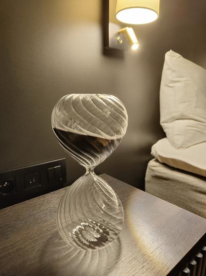 An hourglass on a nightstand by the bed with dark gray sand. I didn't time it, but I suspect it's for one hour, possibly two.