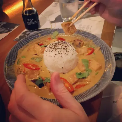 A bowl of food at Wagamamas: a big blob of rice in the middle and a yellow curry around it with red and green veg in it.