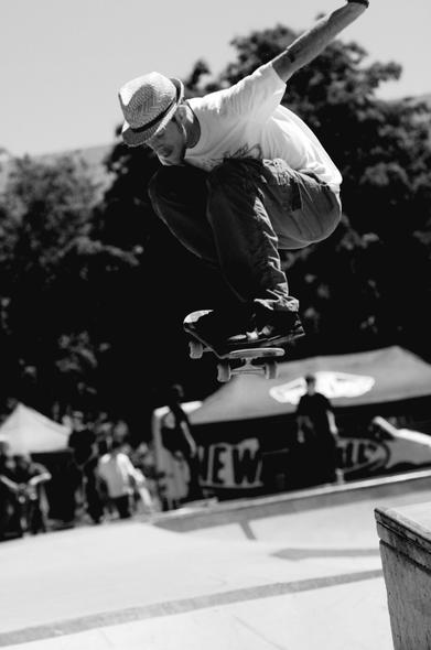 Skateboarder with white tshirt, jeans & Panama fedora hat, doing an aerial trick.