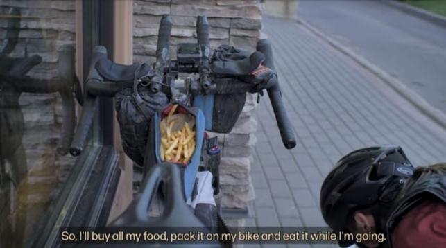 Screenshot aus einem Film: Ein Rad mit Bikepacking-Setup. In der offenen Oberrohr-Tasche sind Pommes zu sehen.