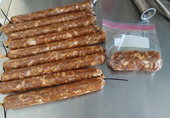 Several freshly stuffed sticks of pepperoni, and a plastic bag containing some more of the meat mixture.