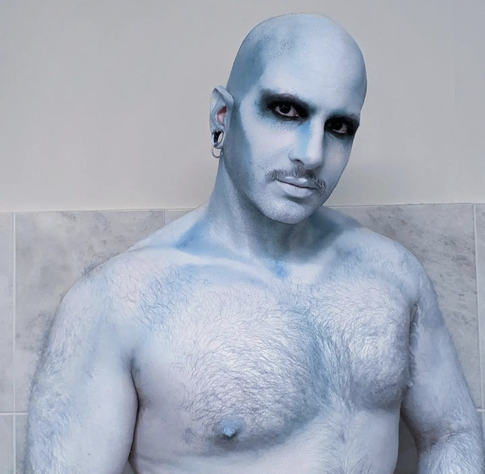 Picture of a man in full white and blue bodypaint looking frosty