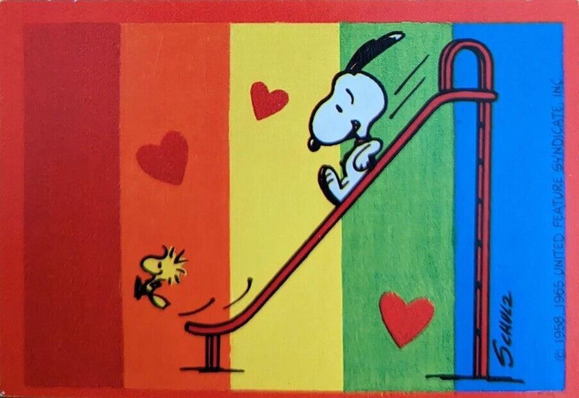 Snoopy chases Woodstock down the slide. Background is a rainbow.