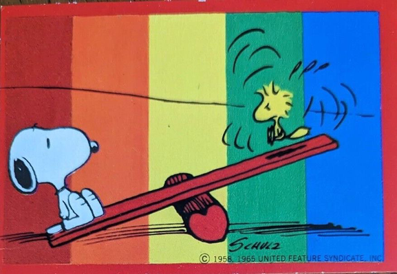 Snoopy and Woodstock play on a teeter totter, rainbow in the background ￼
