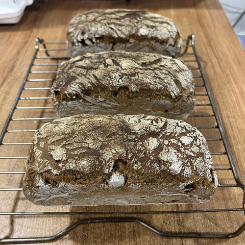The three breads now removed from their tins but still resting on the cooling rack. Since this is not a dough but a batter, it is quite wet. You can use that fact by rolling clumps of it in rye flour and then roughly shaping it like a sausage. You also need to dust the tins with a good layer of flour. When the batter rises in the tins the brown batter and white flour form an attractive looking cracquelé.