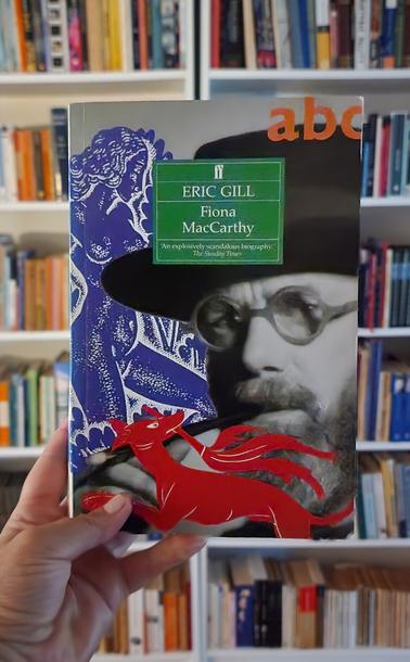 A hand holds up a Faber and Faber book with the title Eric Gill by Fiona MacCarthy.