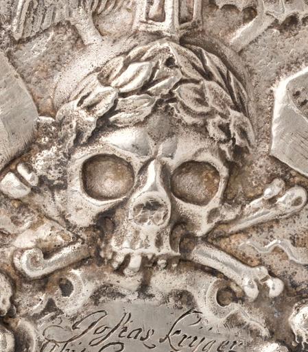 The skull on the medal rests on two crossed bones and wears a wreath.