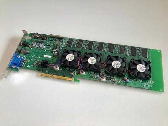 A computer video card prototype photographed on a white surface from the eBay action.

The AGP card lacks branding beyond 4 AAVID cooling fans.

The slot cover appears to have a VGA connector and a barrel connector, presumably for an external power supply.