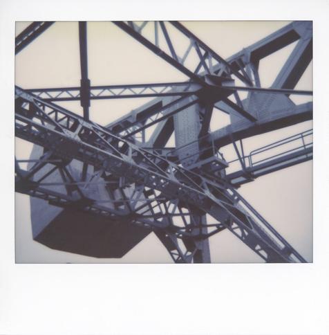 A color Polaroid photograph of the upper girder structure of a bascule bridge showing one of the concrete counterweights.
