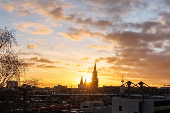 Das Ulmer Münster im Gegenlicht an einem goldenen Morgen mit Wolken.