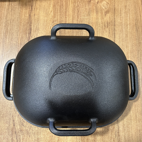 Closeup of my new cast-iron Dutch Oven, from above, with the lid on. There's a pretty corn stalk imprinted on top of the lid, also cast-iron.
