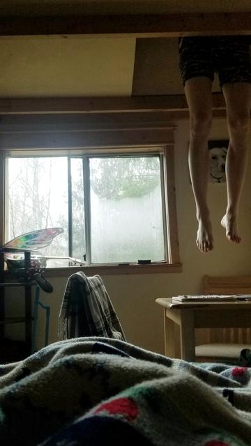 My perspective from bed. Windows, tables & chair.  Friend's bare legs, dangling from cabin extra sleeping loft space.