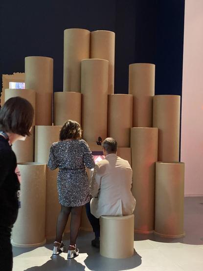 Some people interacting with the installation. The touch screen is surrounded by a semicircle of cardboard tubes of differing heights.
