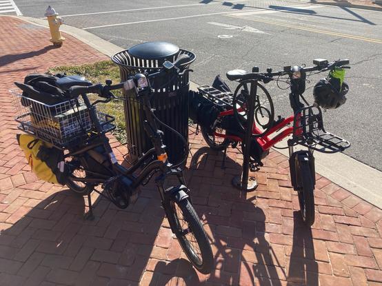 Two electric cargo bikes parked on a sidewalk