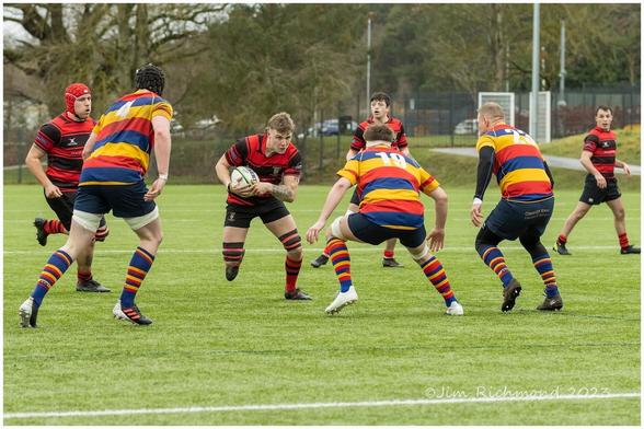 A rugby player in possession of the ball is about to be tackled by an opponent.